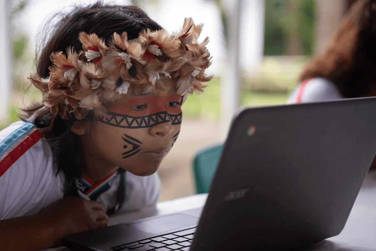 Estudante indígena utilizando um Chromebook durante o projeto em Bertioga